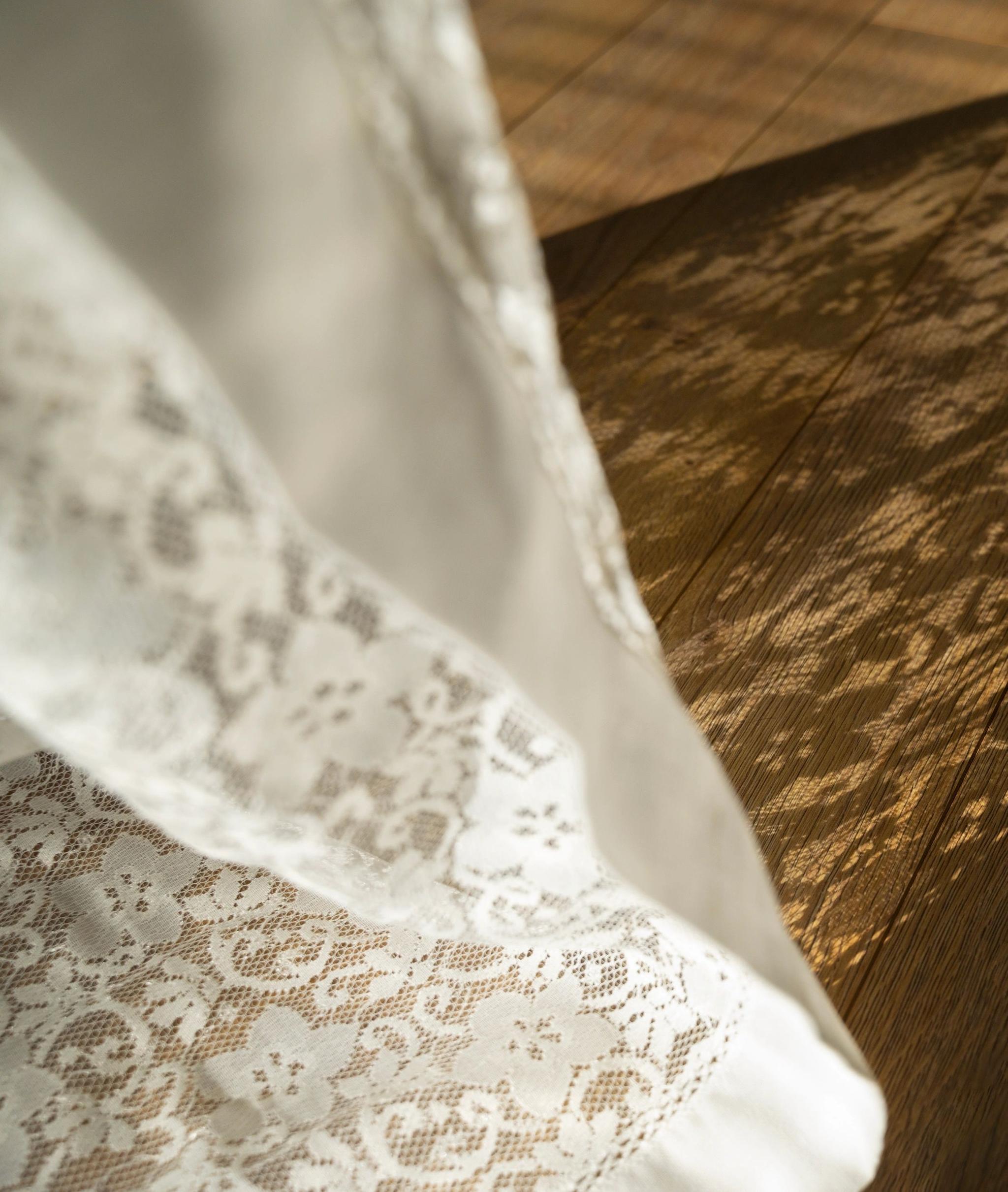 Détail de robe de mariée en dentelle blanche sur parquet dans hôtel à Calenzana